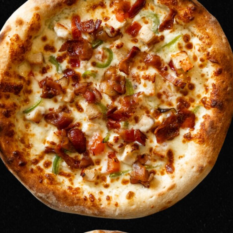 The Half Pint Chicken Bacon Ranch Pizza with grilled chicken, bacon, tomatoes, green peppers, and mozzarella on a ranch base.